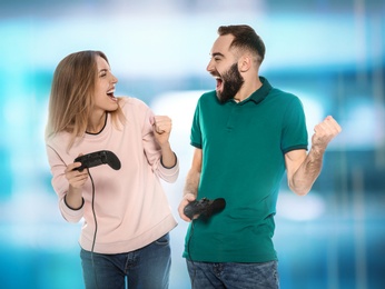 Emotional young couple playing video games with controllers on colorful background