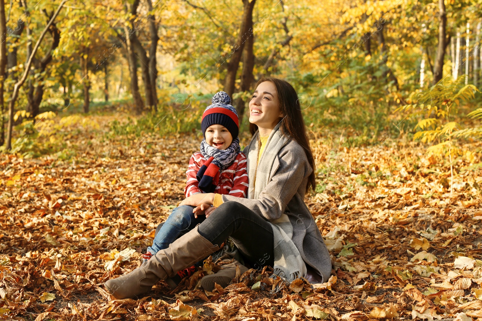 Photo of Mother with her cute son spending time together in park. Autumn walk