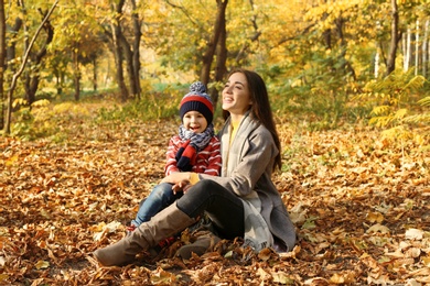 Photo of Mother with her cute son spending time together in park. Autumn walk