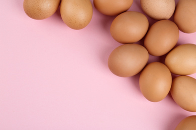 Raw chicken eggs on pink background, flat lay. Space for text