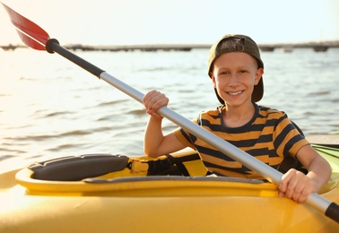 Happy little boy kayaking on river. Summer camp activity