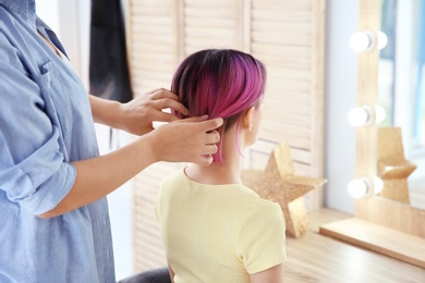 Professional hairdresser working with young woman in beauty salon. Trendy hair color