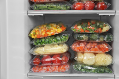 Photo of Plastic bags with different frozen vegetables in refrigerator