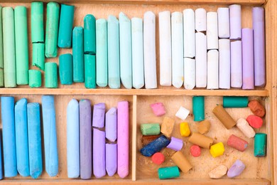 Photo of Set of soft pastels in wooden box as background, top view. Drawing material
