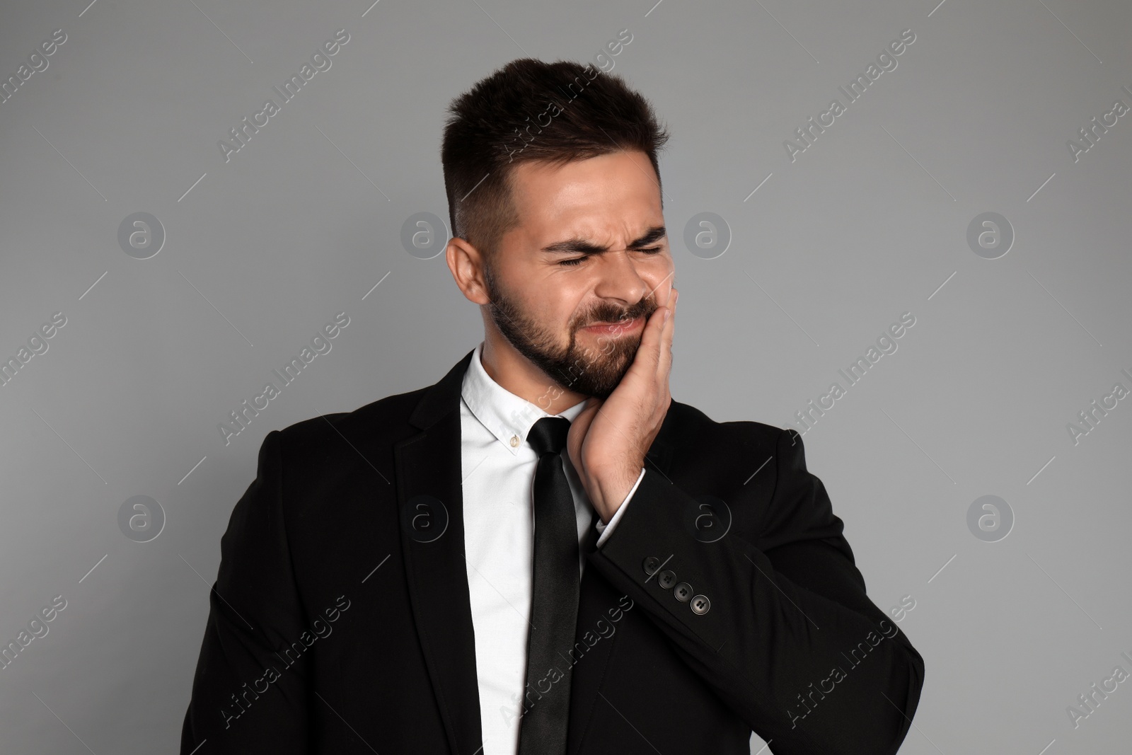 Photo of Businessman suffering from toothache on light grey background