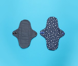 Reusable cloth menstrual pads on light blue background, flat lay