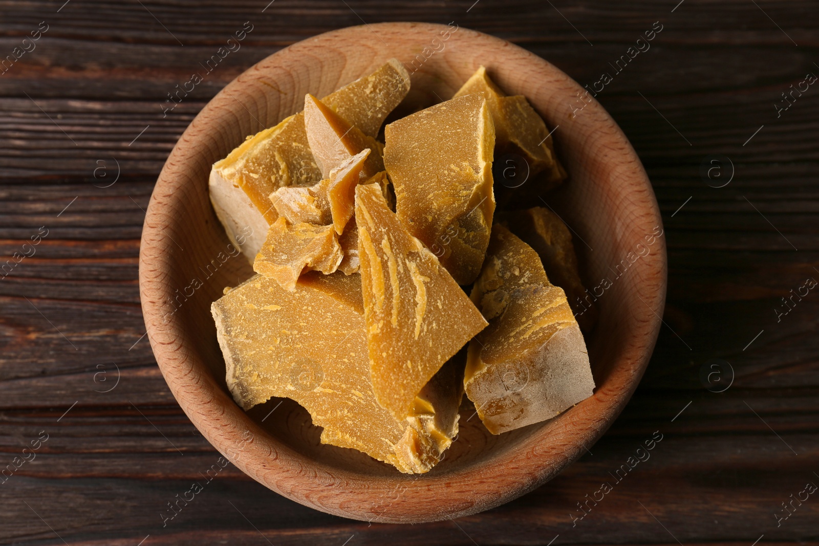 Photo of Bowl with natural beeswax blocks on wooden table, top view