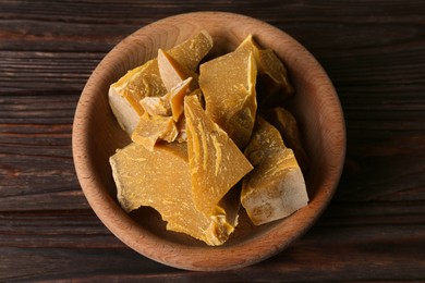Photo of Bowl with natural beeswax blocks on wooden table, top view