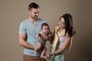 Photo of Happy family. Couple with their cute baby on beige background