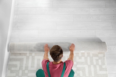 Photo of Man rolling out new carpet flooring indoors, top view. Space for text