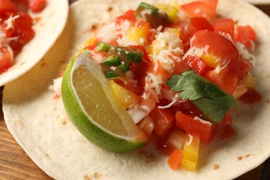 Photo of Delicious taco with vegetables, lime and ketchup on wooden table, closeup