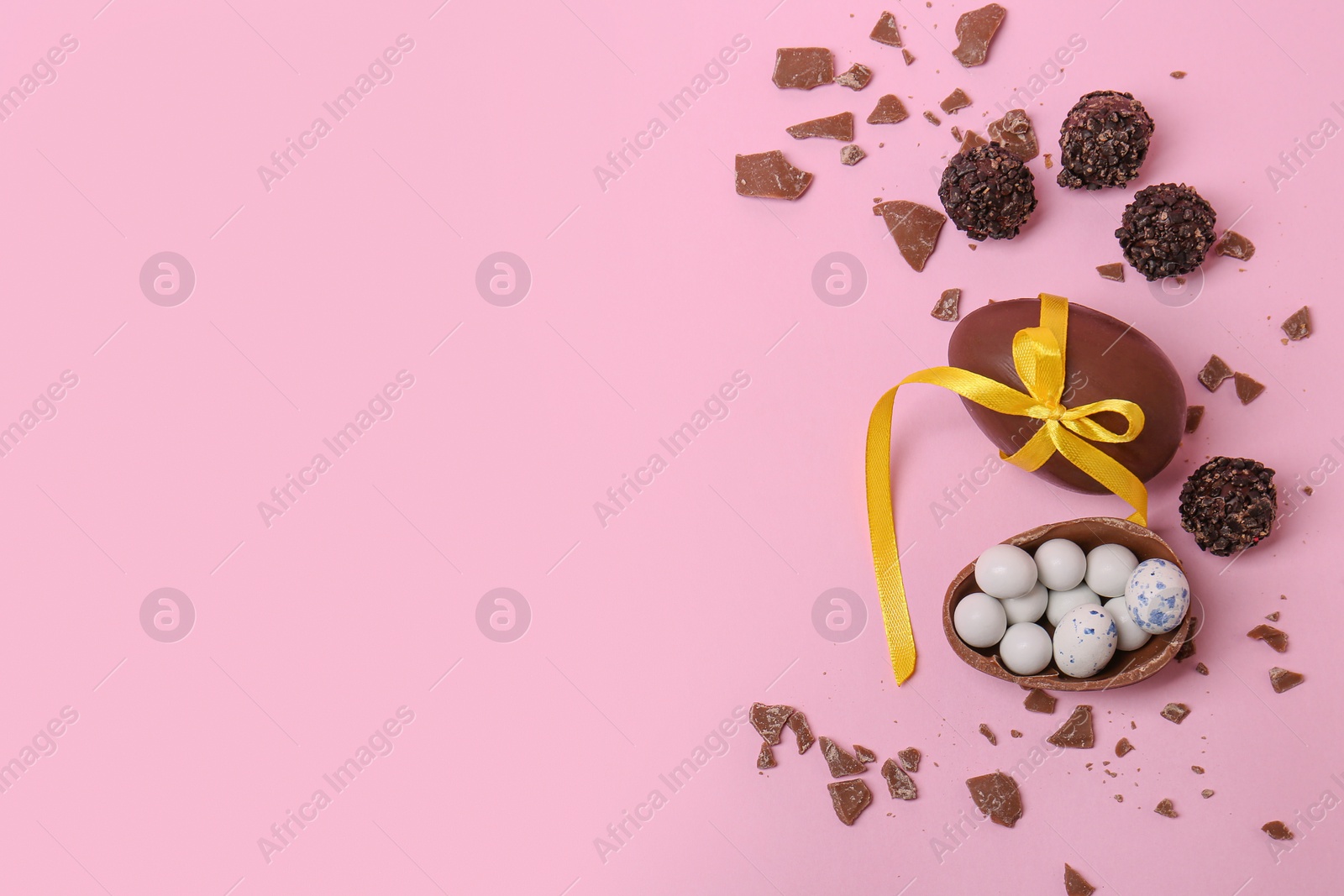 Photo of Tasty chocolate eggs and candies on pink background, flat lay. Space for text