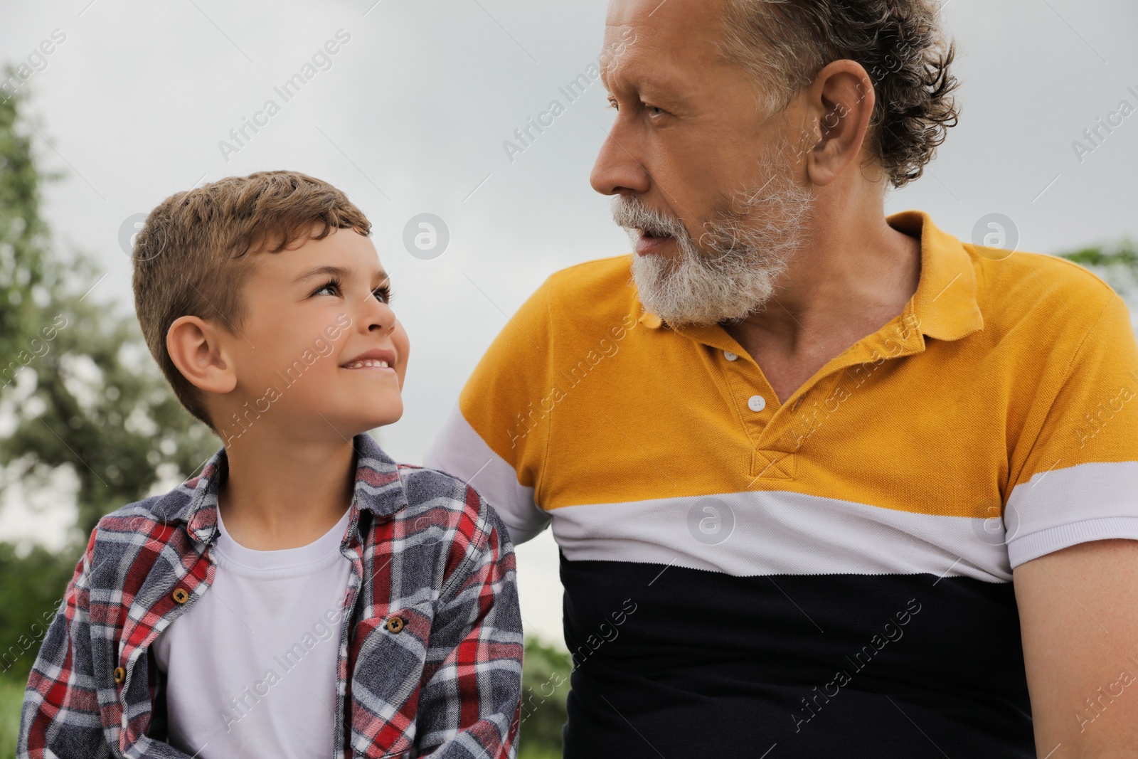 Photo of Cute little boy and grandfather spending time together in park