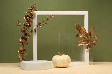 Photo of Autumn presentation for product. Geometric figures, pumpkin and branch with golden leaves on color background