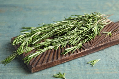 Photo of Wooden board with fresh rosemary twigs on table