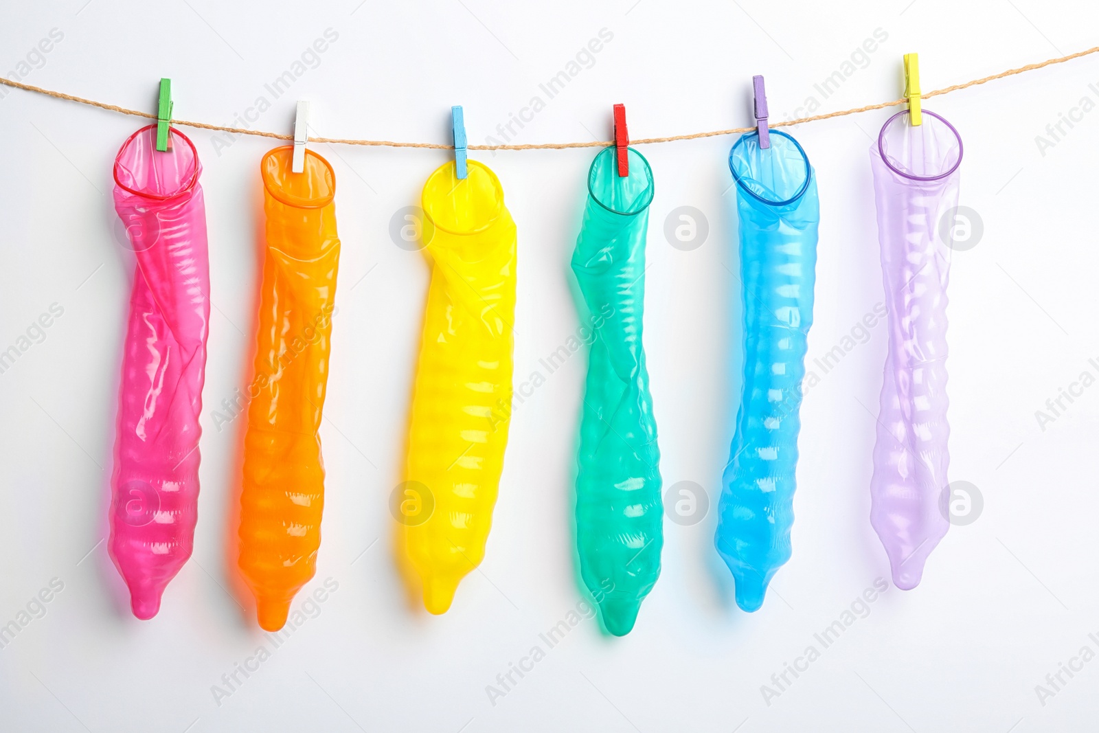 Photo of Used colorful condoms hanging on clothesline against white background. Safe sex concept