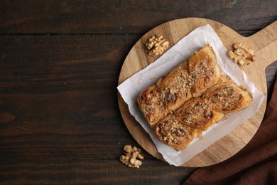 Photo of Eastern sweets. Pieces of tasty baklava and walnuts on wooden table, top view. Space for text