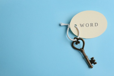 Photo of Vintage key with tag on light blue background, top view and space for text. Keyword concept