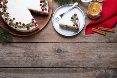 Flat lay composition with traditional Christmas cake on wooden table. Space for text
