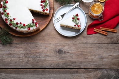 Photo of Flat lay composition with traditional Christmas cake on wooden table. Space for text