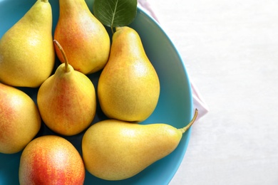 Photo of Plate with ripe pears on light background, closeup. Space for text