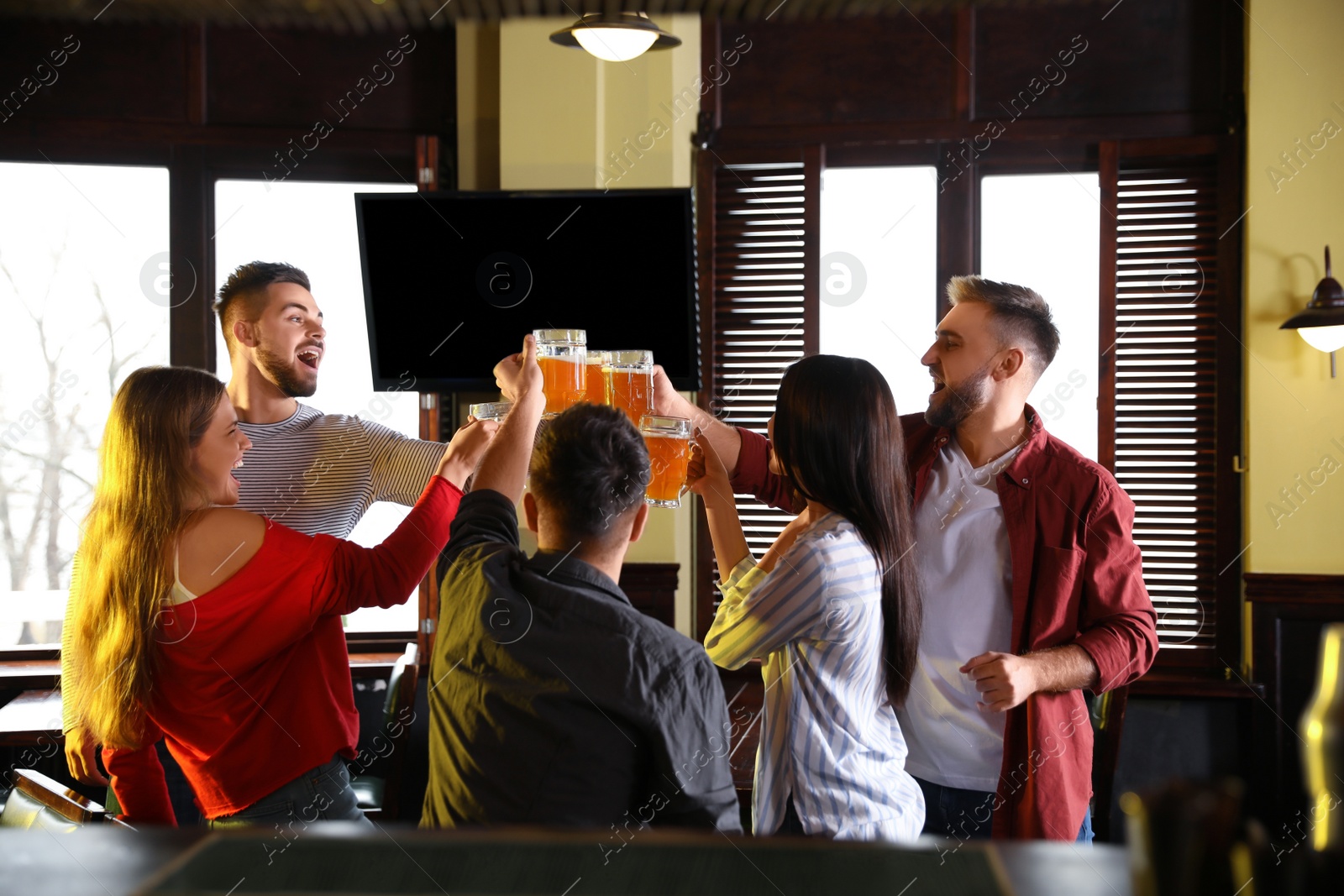 Photo of Group of friends celebrating victory of favorite football team in sport bar