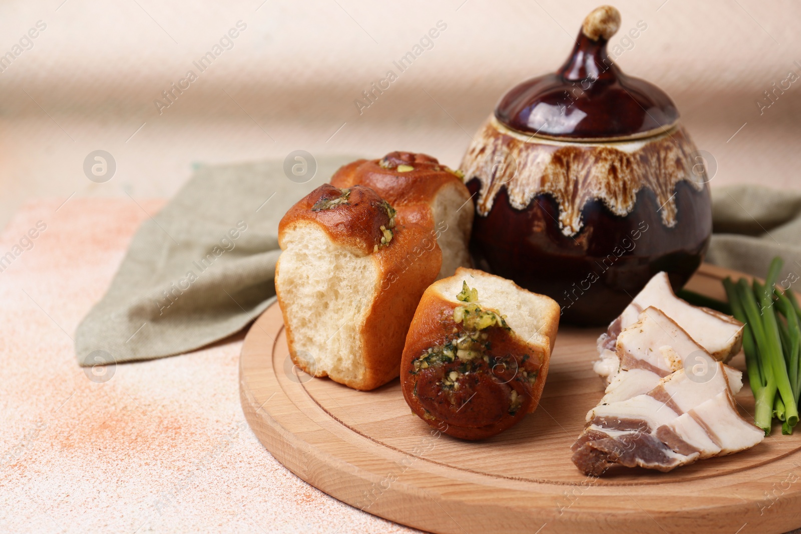 Photo of Delicious pampushky (buns with garlic), salo and green onions served for borsch on color textured table, space for text