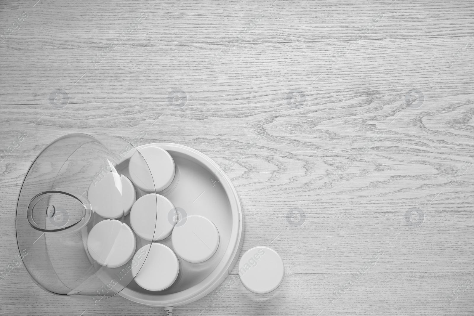 Photo of Modern yogurt maker with jars on white wooden table, flat lay. Space for text