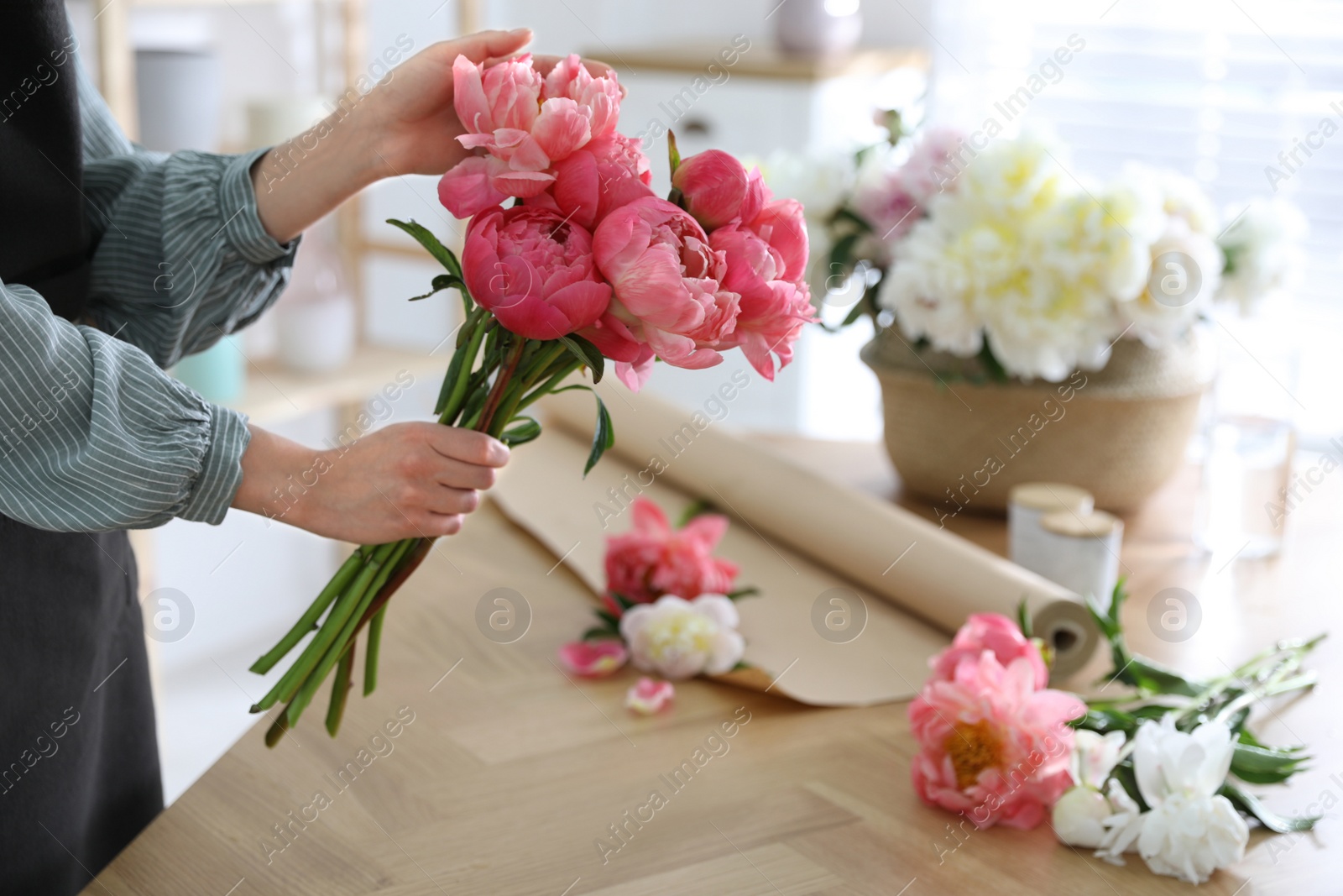 Photo of Florist making beautiful peony bouquet at table, closeup