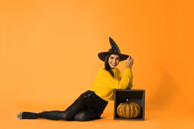 Photo of Beautiful woman wearing witch costume for Halloween party on yellow background