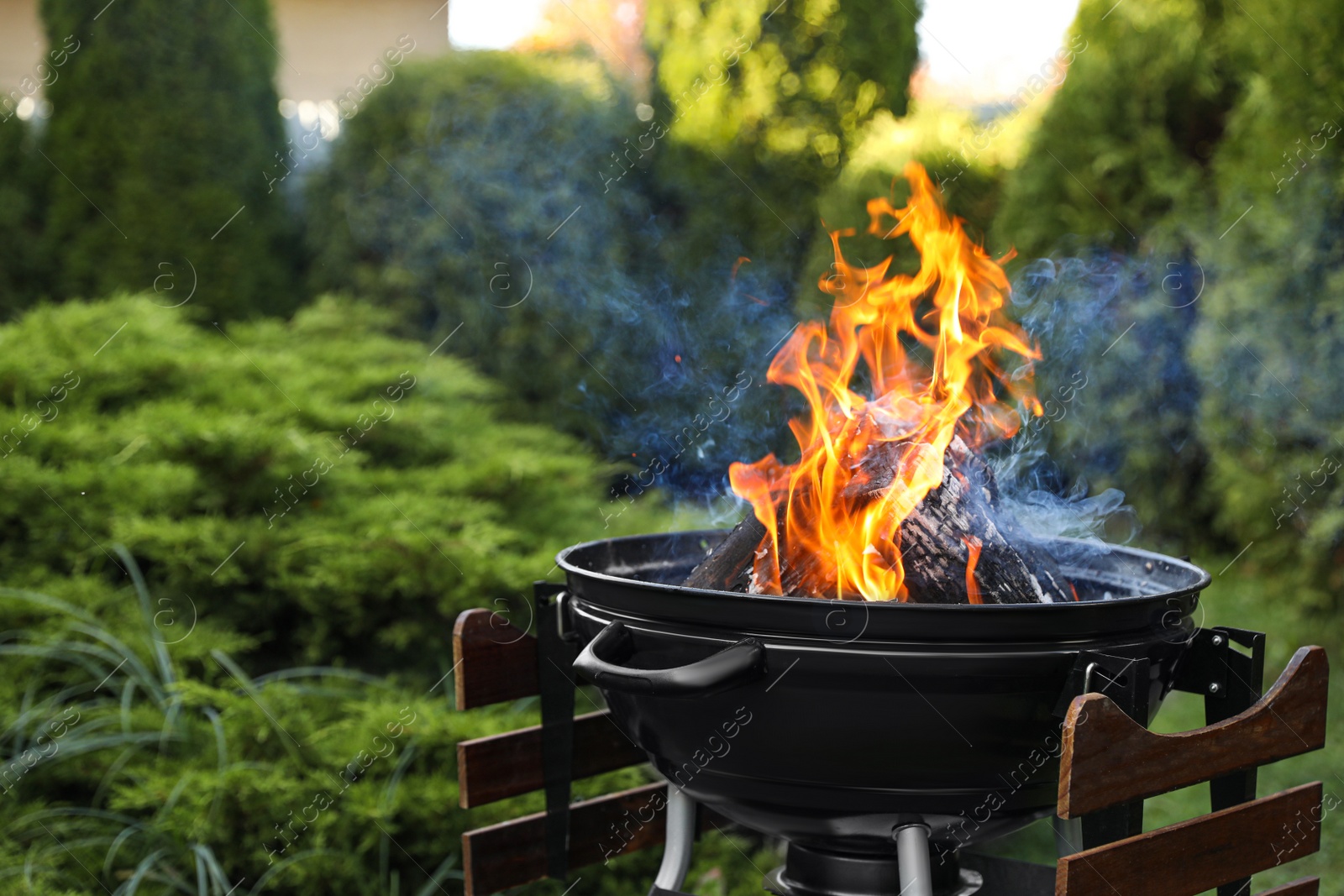 Photo of Portable barbecue grill with fire flames outdoors. Space for text