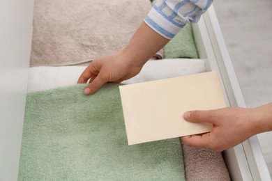Woman putting scented sachet into drawer with towels, closeup