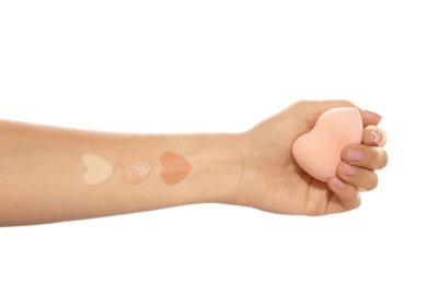 Woman with different foundation swatches on her hand against white background, closeup