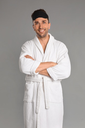 Photo of Happy young man in bathrobe on grey background