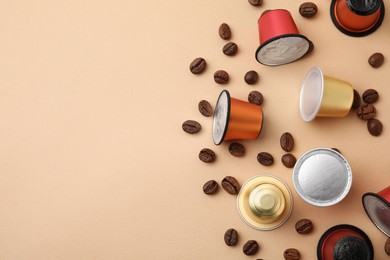 Photo of Many coffee capsules and beans on beige background, flat lay. Space for text