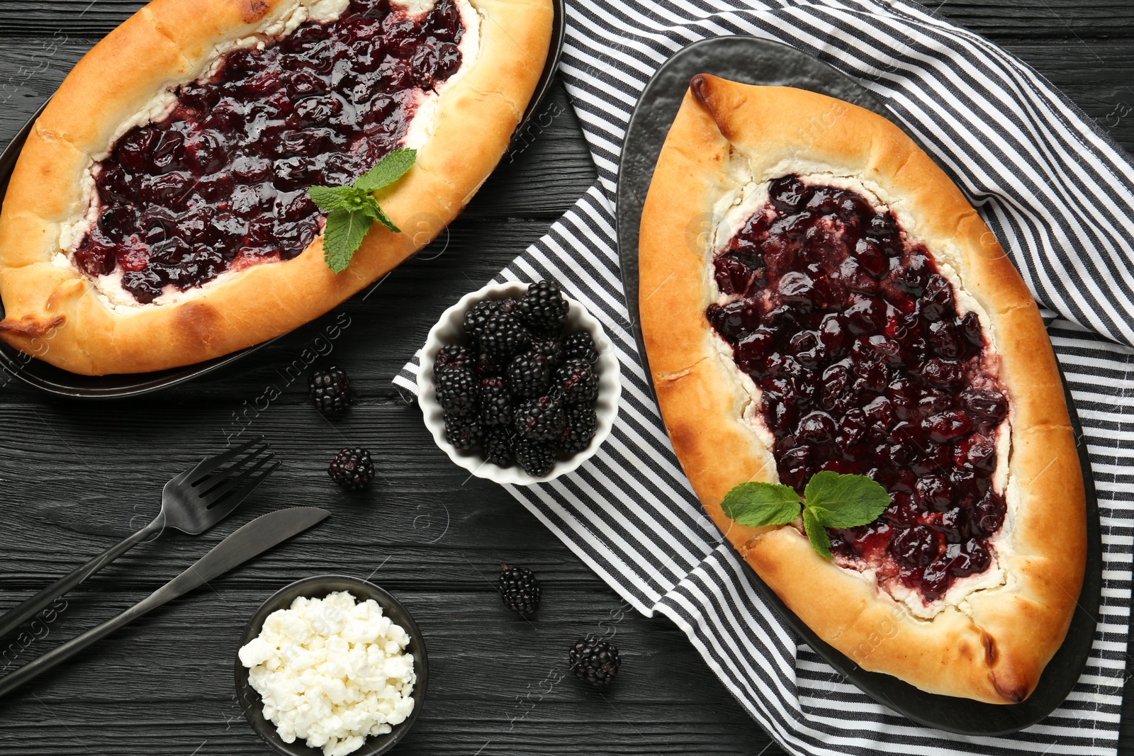 Photo of Delicious sweet cottage cheese pastry with cherry jam served on black wooden table, flat lay