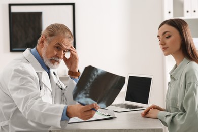 Photo of Orthopedist showing X-ray picture to patient in clinic