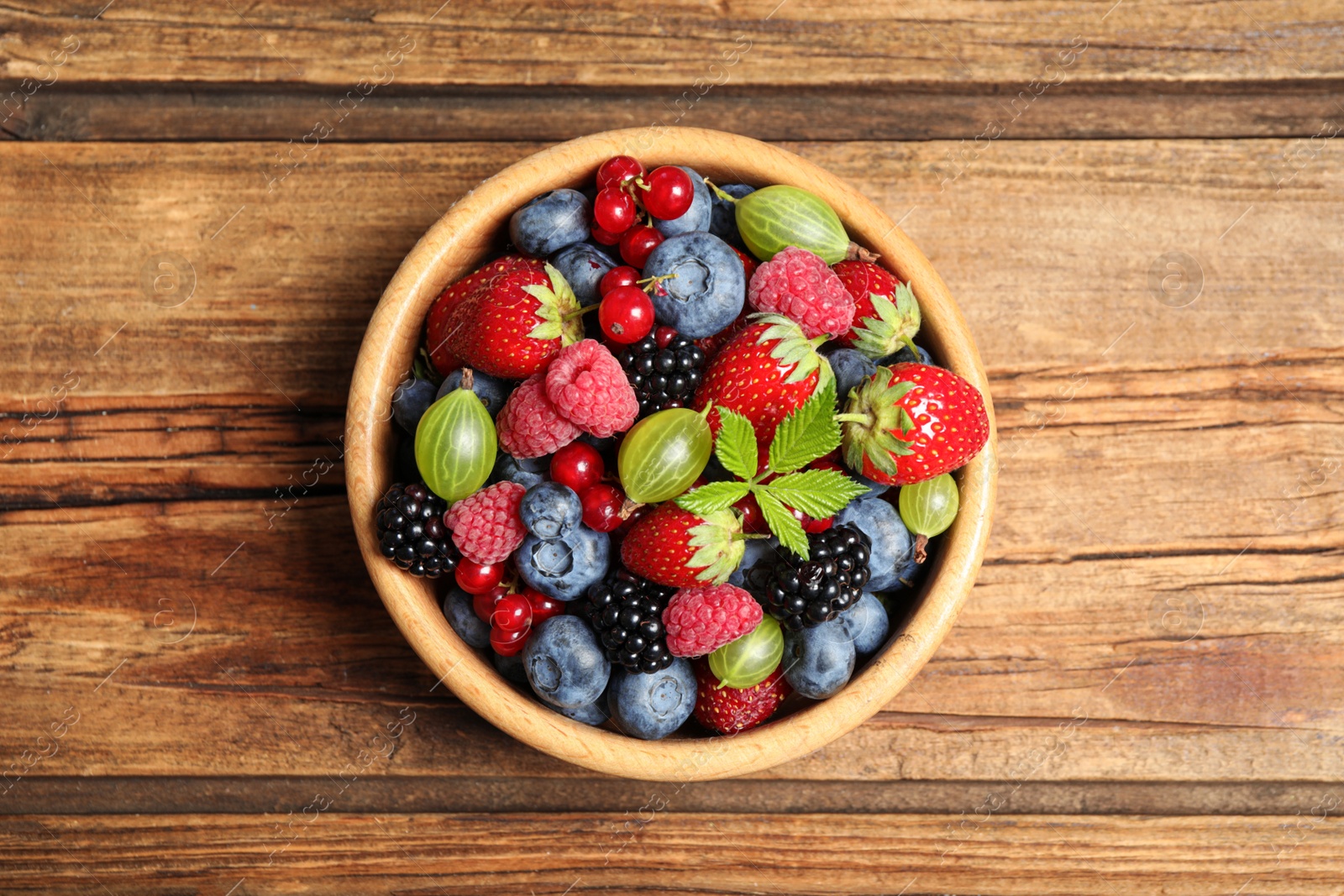 Photo of Mix of ripe berries on wooden table, top view