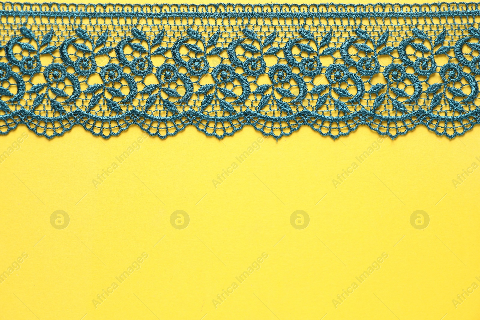 Photo of Green lace on yellow background, top view. Space for text