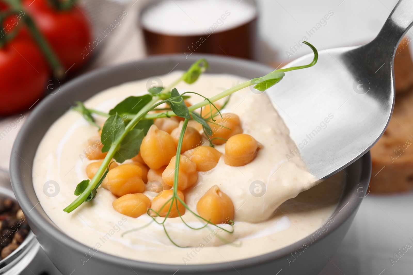 Photo of Eating tasty chickpea soup on table, closeup