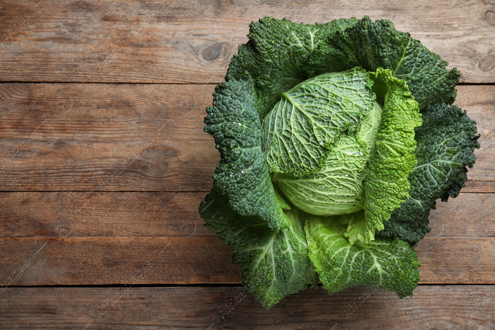 Photo of Fresh ripe savoy cabbage on wooden table, top view. Space for text