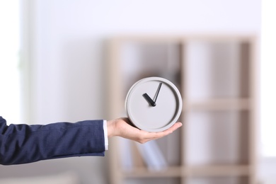 Photo of Businesswoman holding alarm clock on blurred background. Time concept