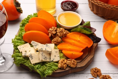 Delicious persimmon, blue cheese, nuts and honey served on white wooden table
