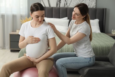 Doula taking care of pregnant woman in bedroom. Preparation for child birth