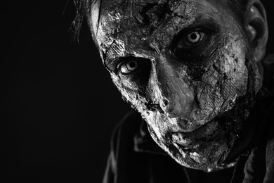 Photo of Scary zombie on dark background, black and white effect. Halloween monster