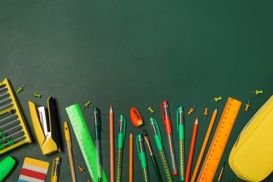 Flat lay composition with different school stationery on chalkboard surface