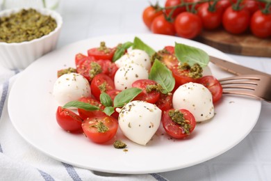 Tasty salad Caprese with tomatoes, mozzarella balls and basil on white table, closeup