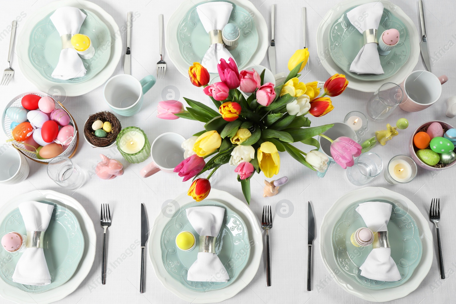 Photo of Easter celebration. Festive table setting with beautiful flowers and painted eggs, flat lay