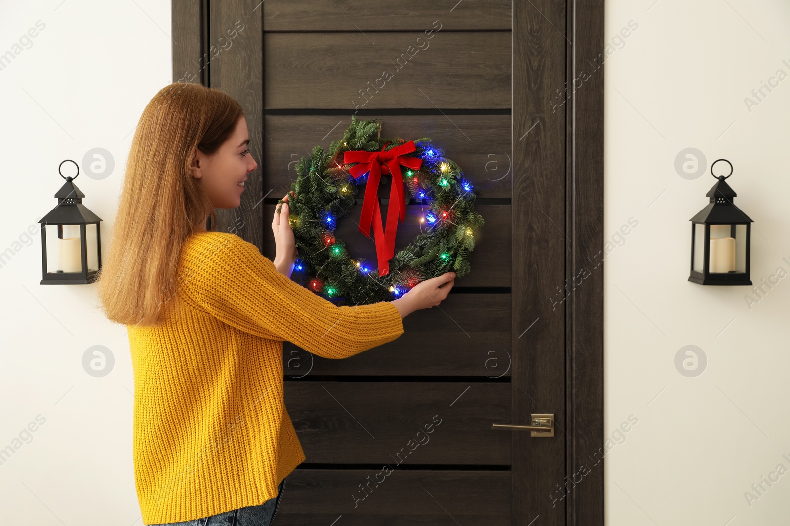 Photo of Woman decorating door with beautiful Christmas wreath