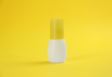 Bottle with insect repellent spray on yellow background